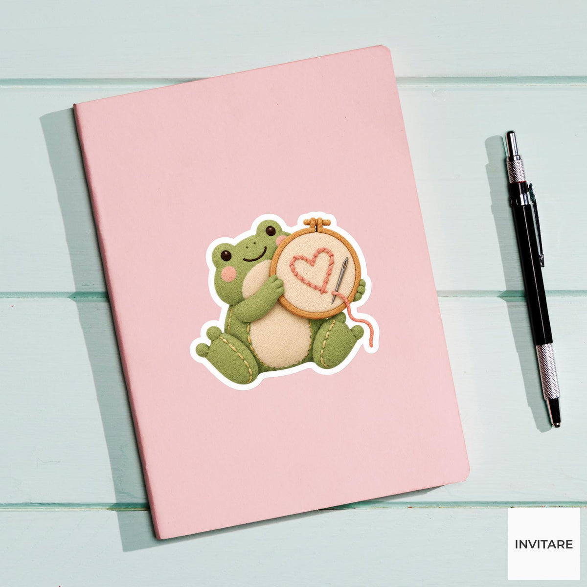 Frog holding up an embroidery hoop with a lopsided heart Vinyl Sticker