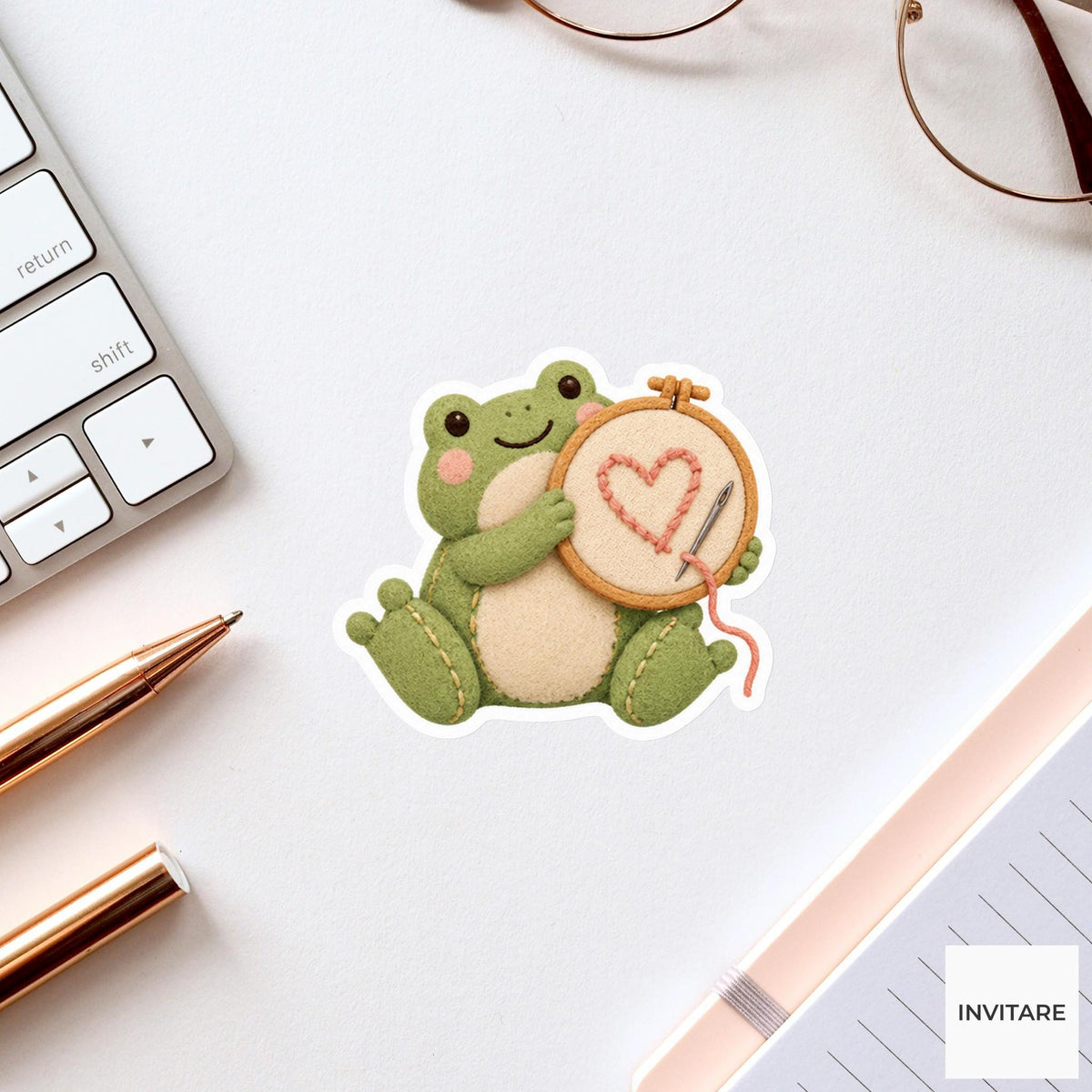 Frog holding up an embroidery hoop with a lopsided heart Vinyl Sticker