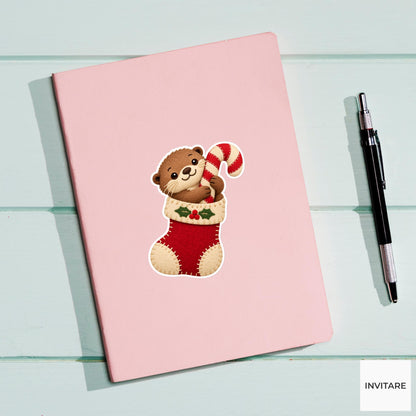 Otter leaning out of a stocking to hug a peppermint candy cane Vinyl Sticker
