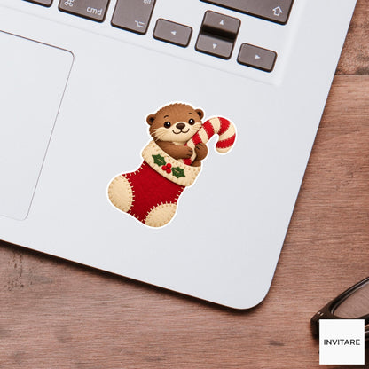 Otter leaning out of a stocking to hug a peppermint candy cane Vinyl Sticker